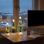 Drie decoratieve kerstboompjes verlichten een feestelijke ruimte