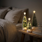 Drie kleine kerstbomen met sfeervolle verlichting