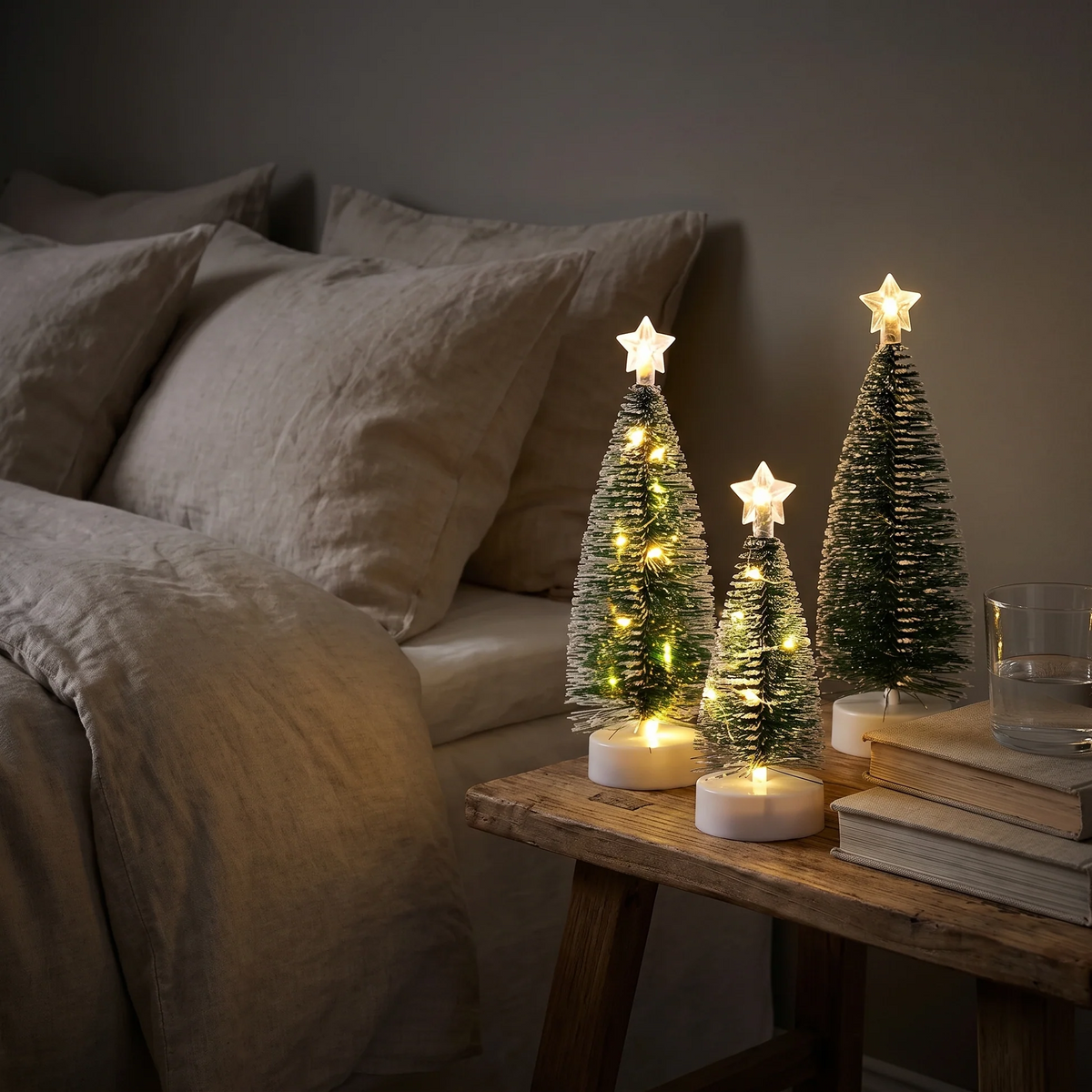 Drie kleine kerstbomen met sfeervolle verlichting